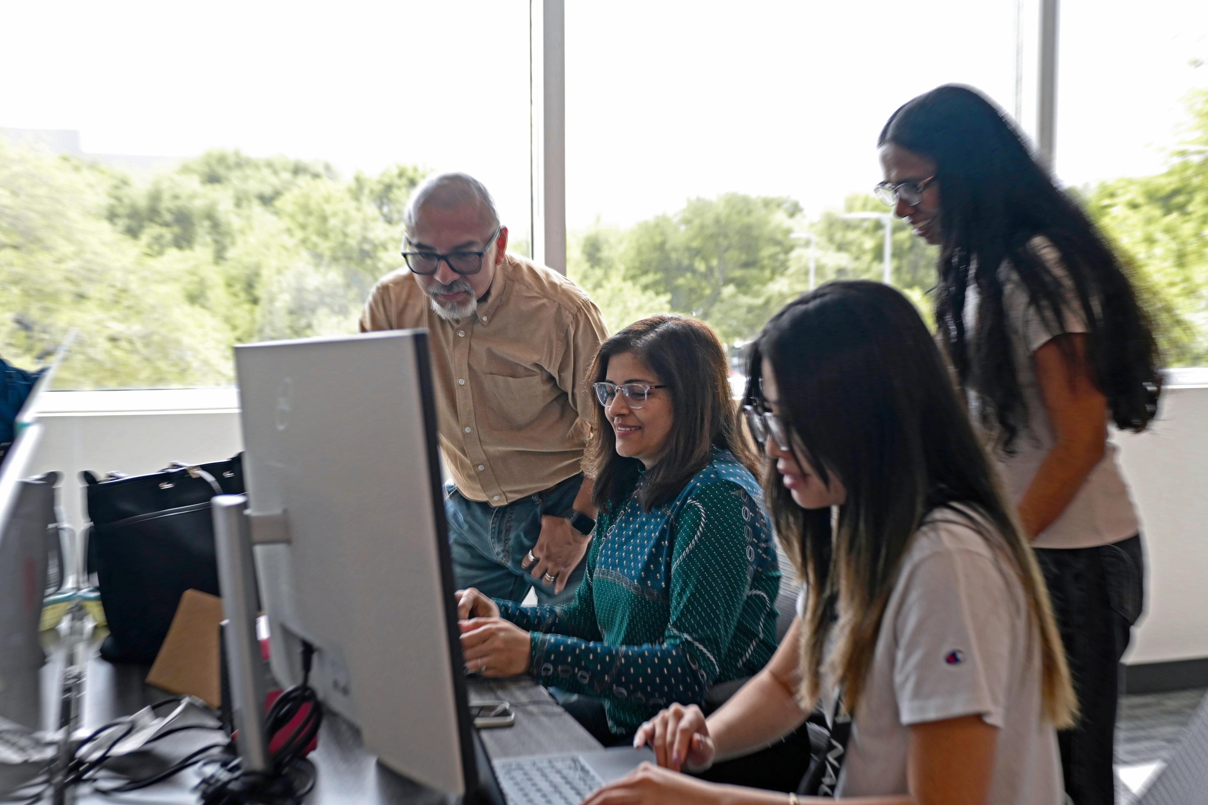 Team members collaborating around a computer